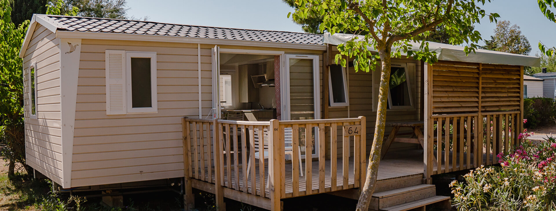 Buitenaanzicht van de stacaravan met 3 slaapkamers en 6-8 slaapplaatsen met halfoverdekt buitenterras, te huur op camping Cap du Roc in Port-la-Nouvelle.